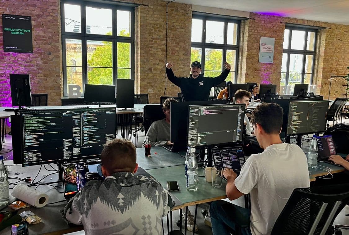 Builderz co-working session at Solana Build Station Berlin—engineers at multi-monitor desks in a brick loft.