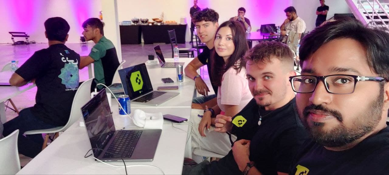 Historical group selfie of Builderz founders and team at Dubai Solana Hacker House with laptops open.